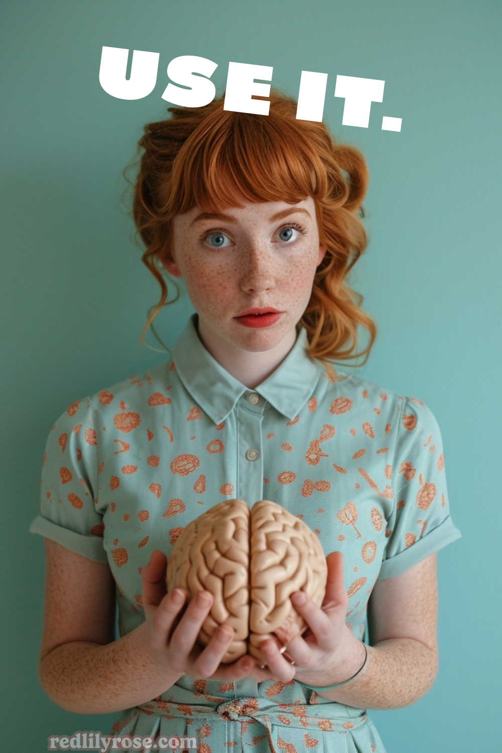 A freckled redhead holding a brain model, with an earnest expression, wearing a teal dress adorned with an orange floral pattern. The words "USE IT." in bold, white font overlay the image at the top, and the website address "redlilyrose.com" is displayed at the bottom.